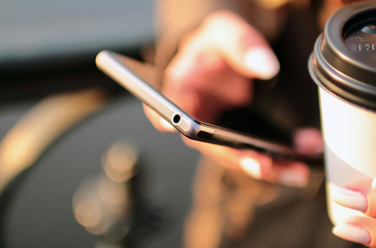 Person using a smartphone with coffee